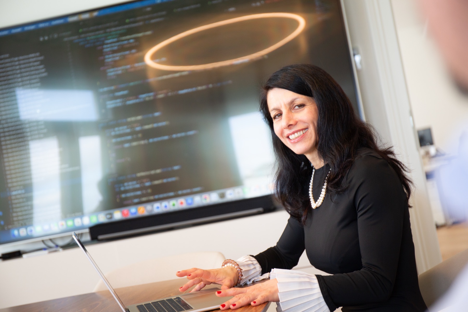 A SYN IT colleague working at a laptop in front of a large screen in the Vienna office.