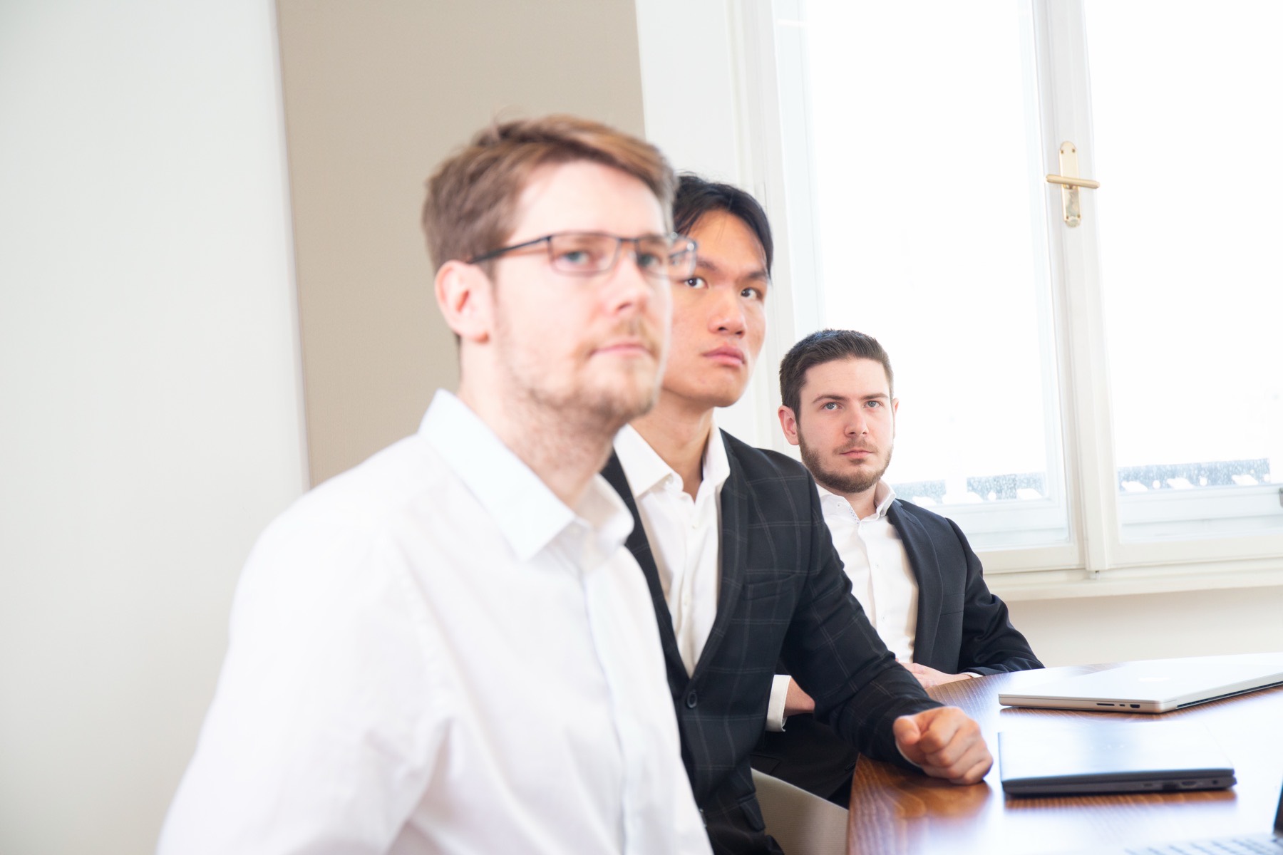 Three colleagues reviewing something together at the meeting table in the office.