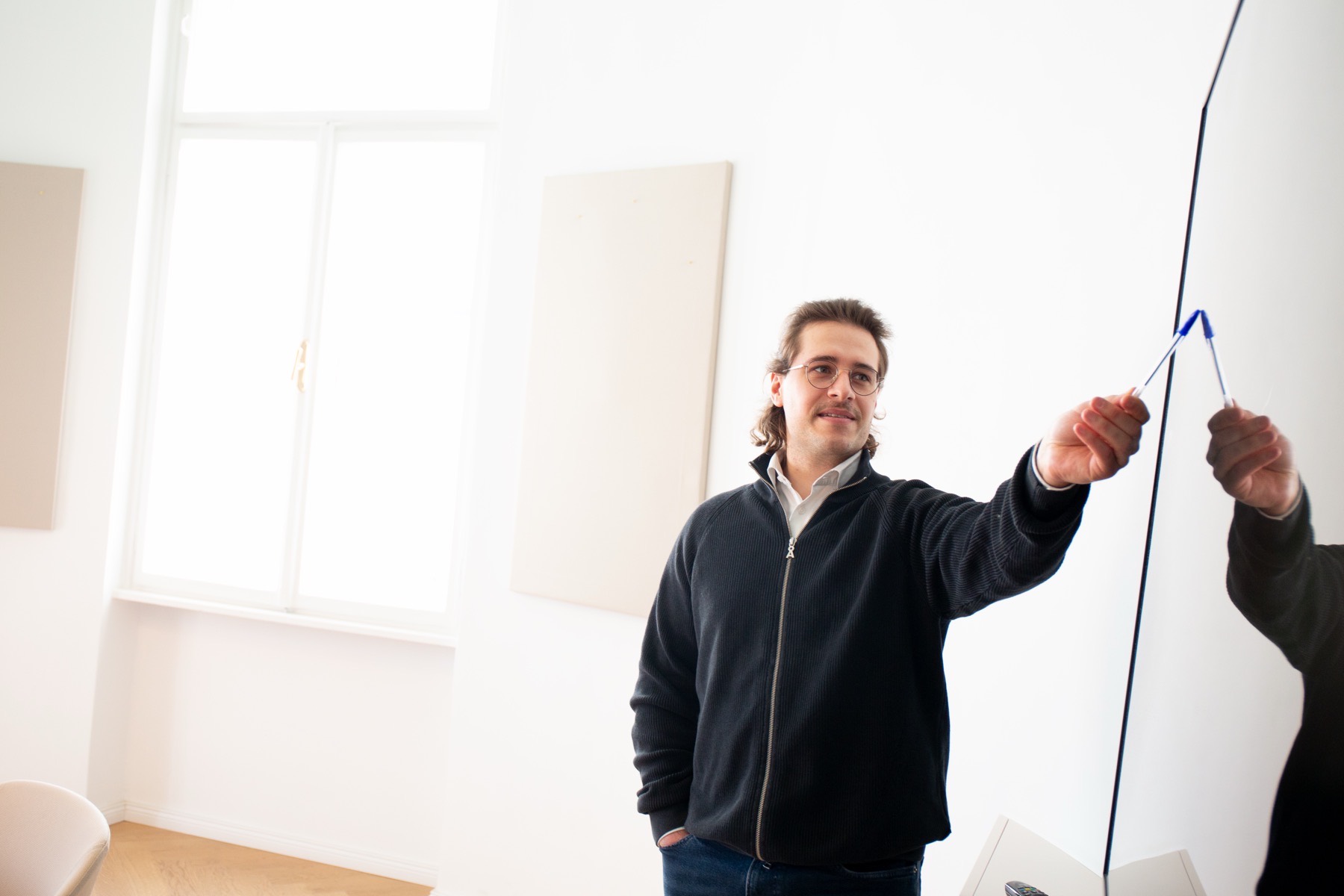 A colleague sketching a solution on a whiteboard while the rest of the group follows.